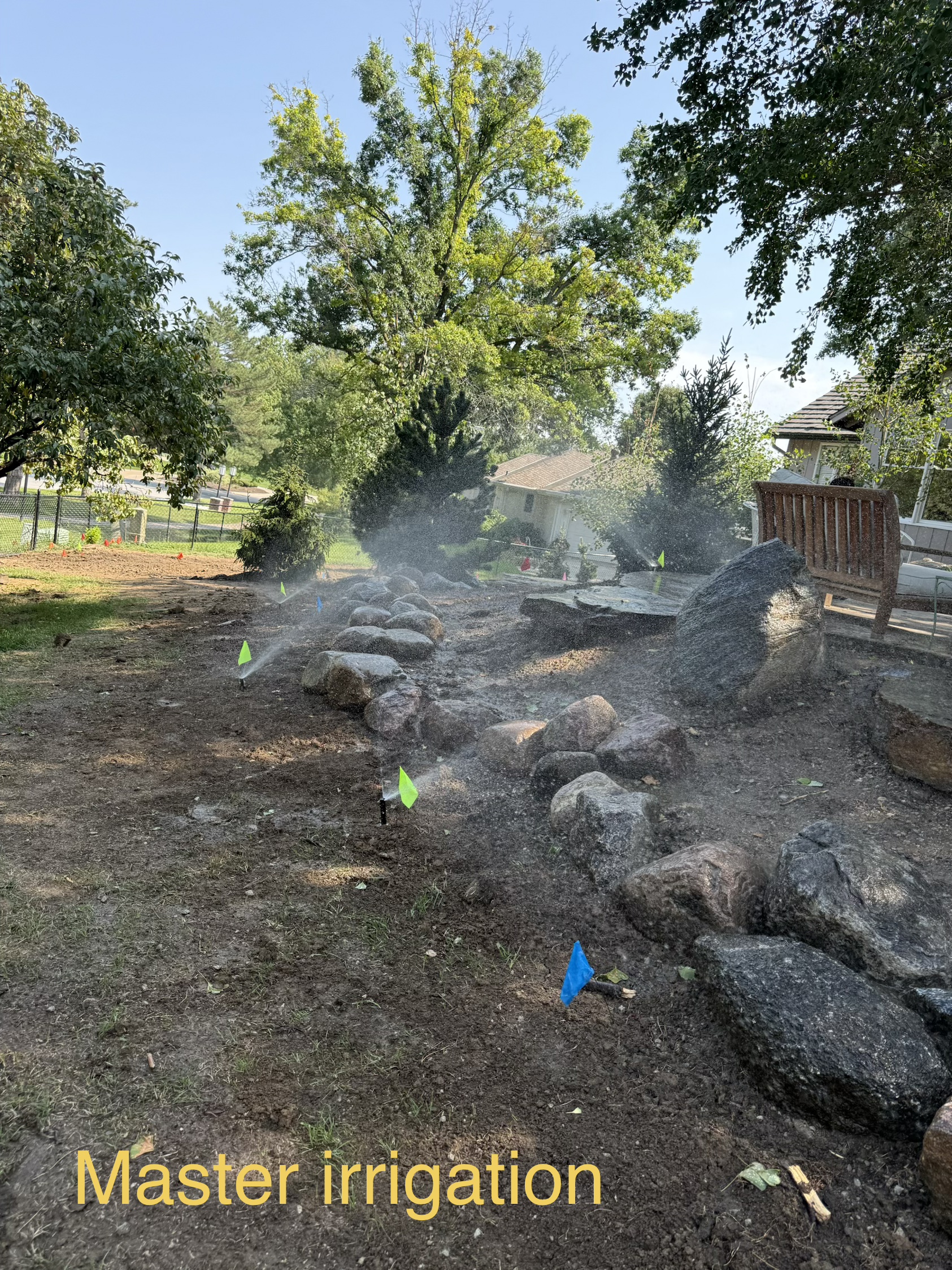 Irrigation zone install among landscape boulders, sprinkler heads running